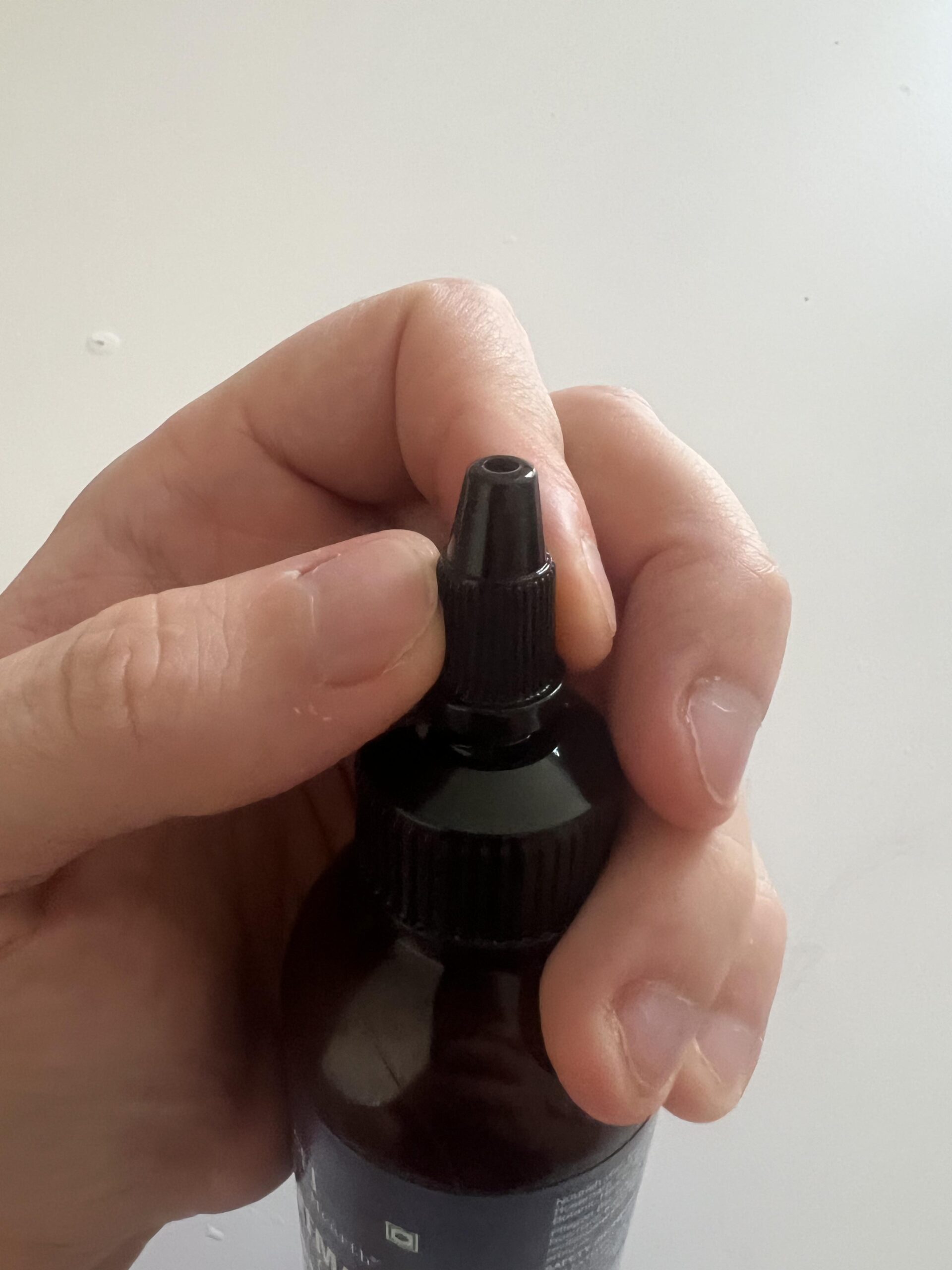 Close-up of the narrow screw-on nozzle of Botanic Hearth Rosemary Hair Oil bottle