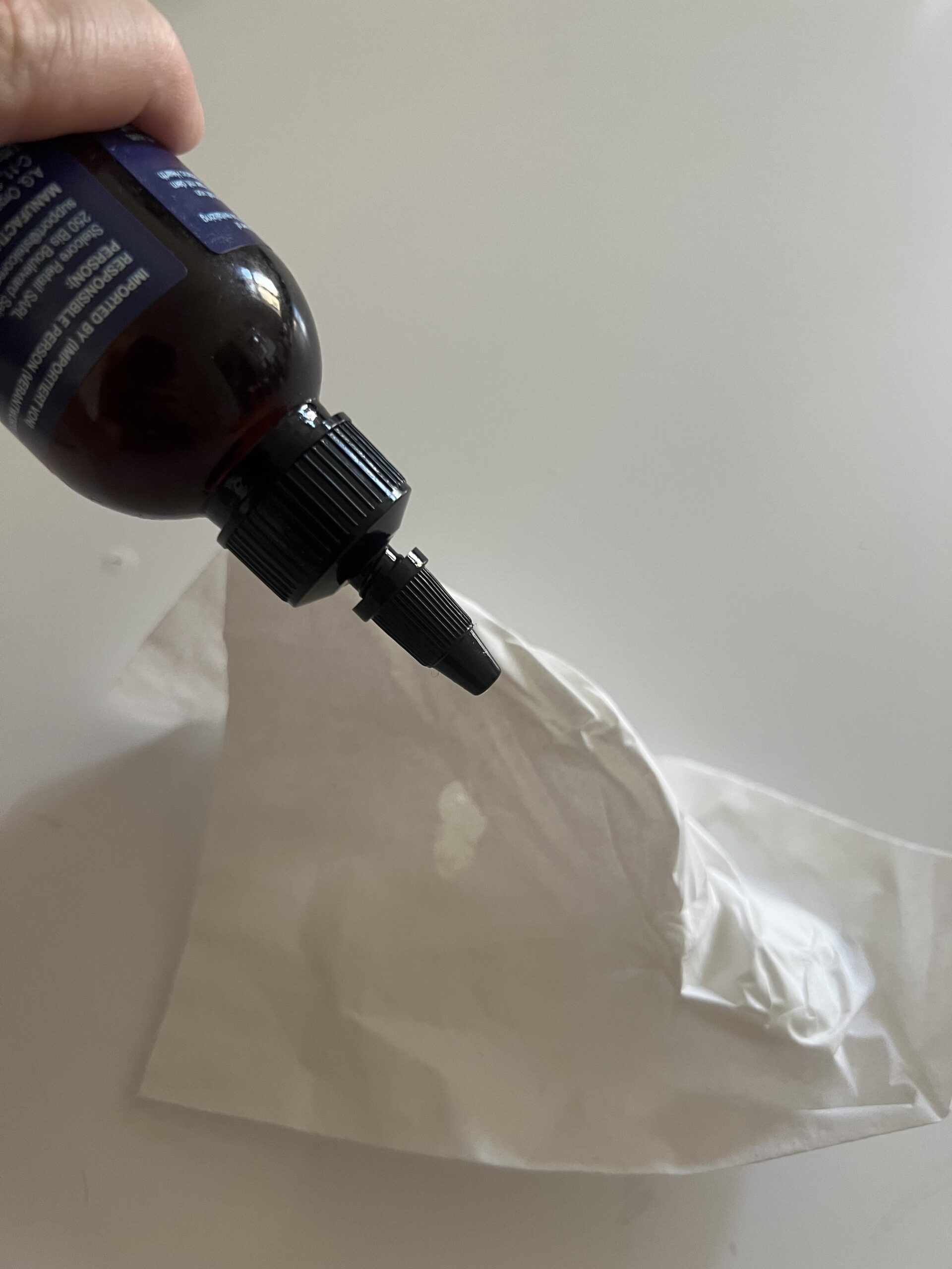 Botanic Hearth Rosemary Hair Oil bottle tilted over white tissue to demonstrate its applicator