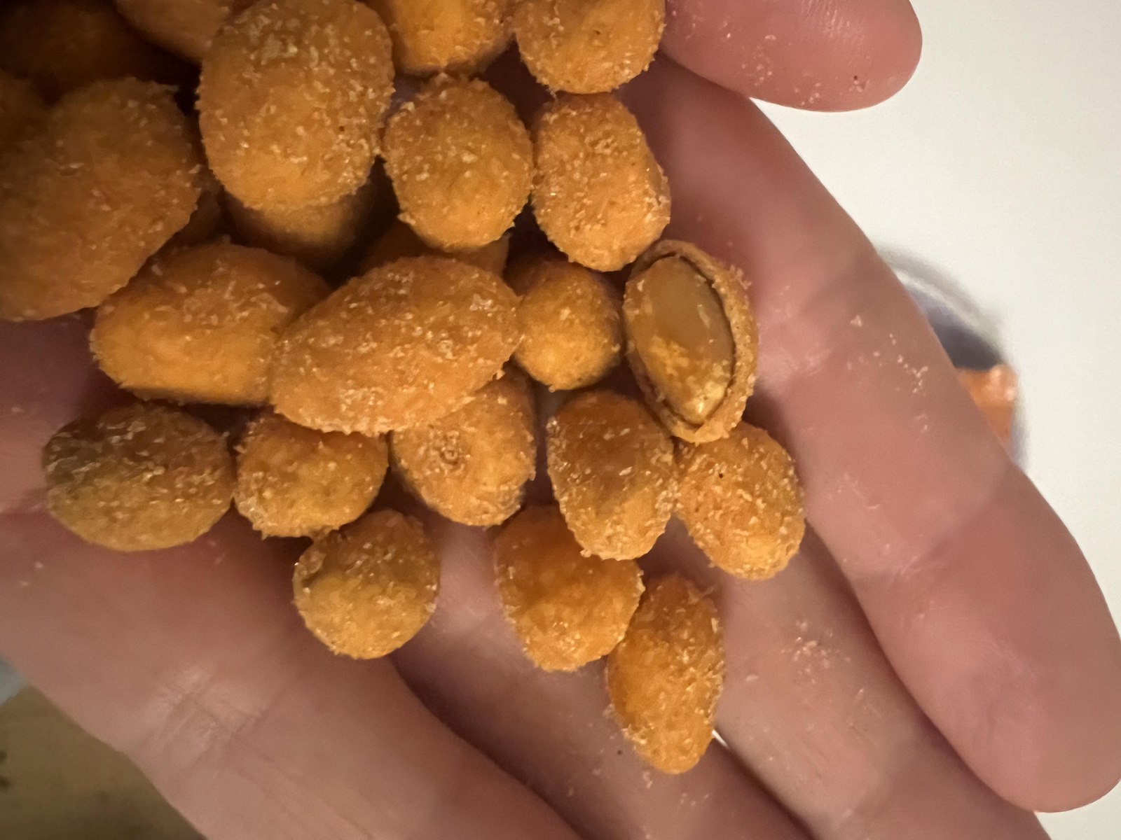 Close-up of a paprika-coated peanut split open to reveal the nut under its crunchy dough layer