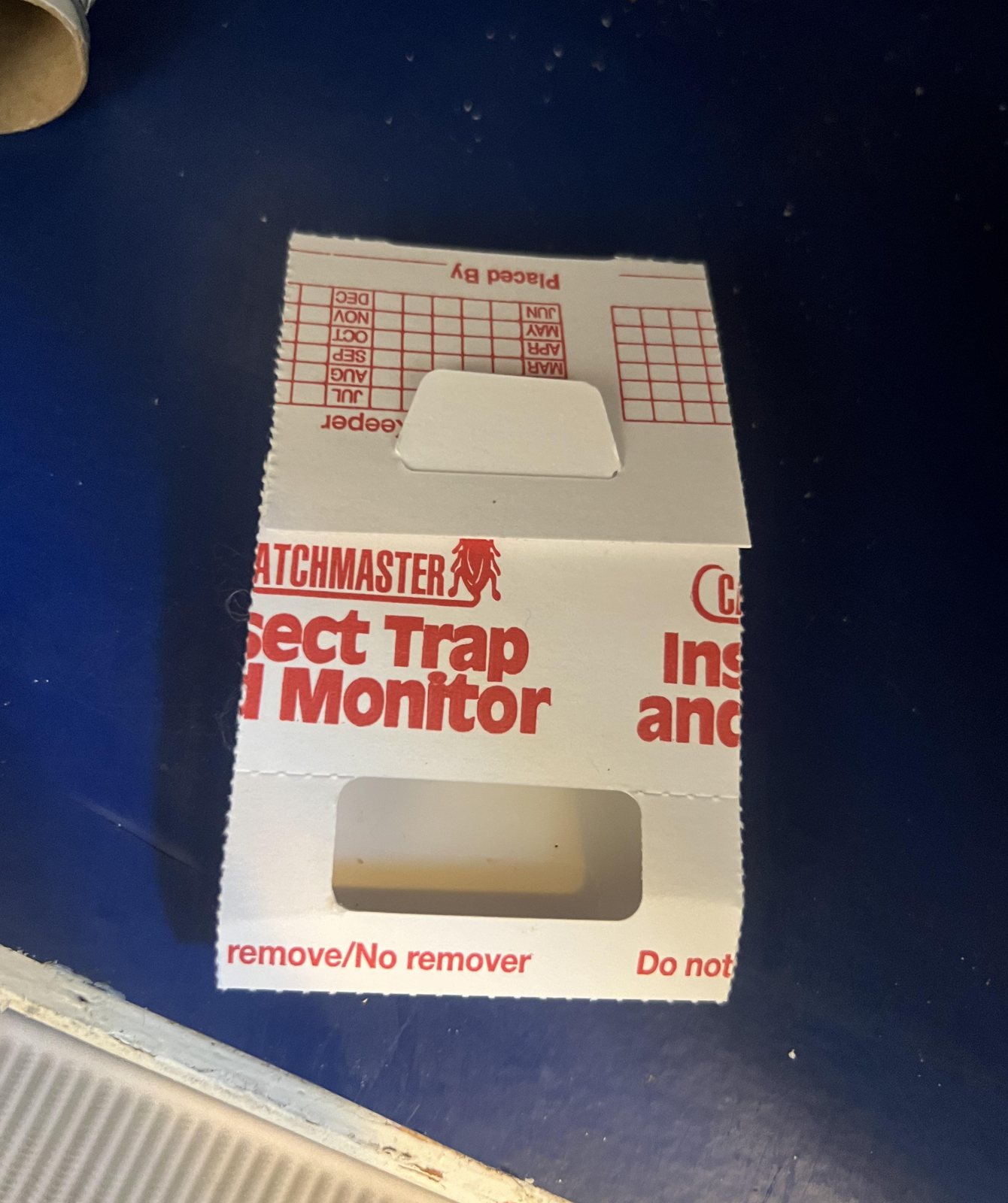 Catchmaster 288i cardboard insect trap hidden on a dark surface among household objects