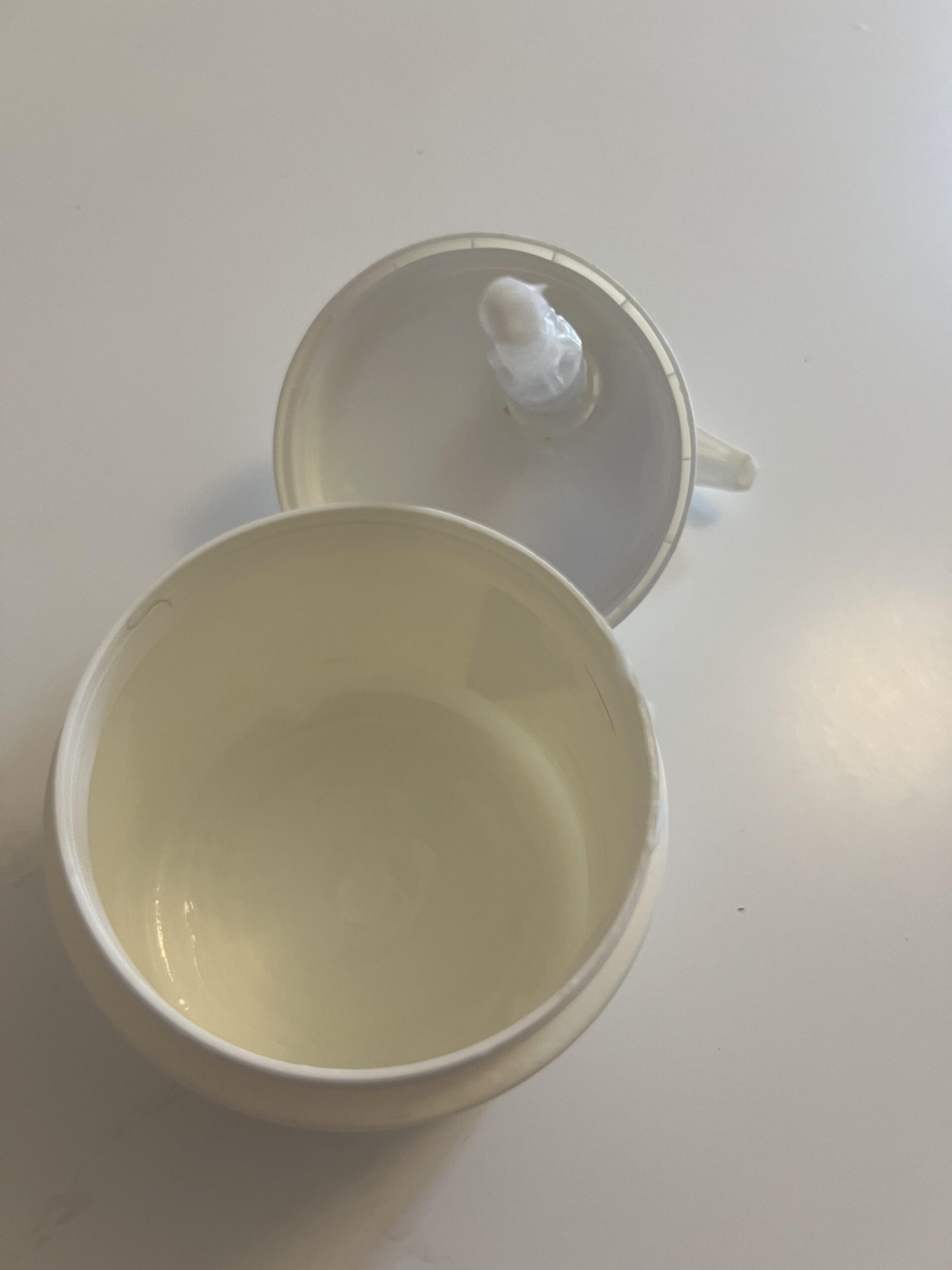 Opened nearly empty CeraVe jar showing remaining cream and detached pump lid
