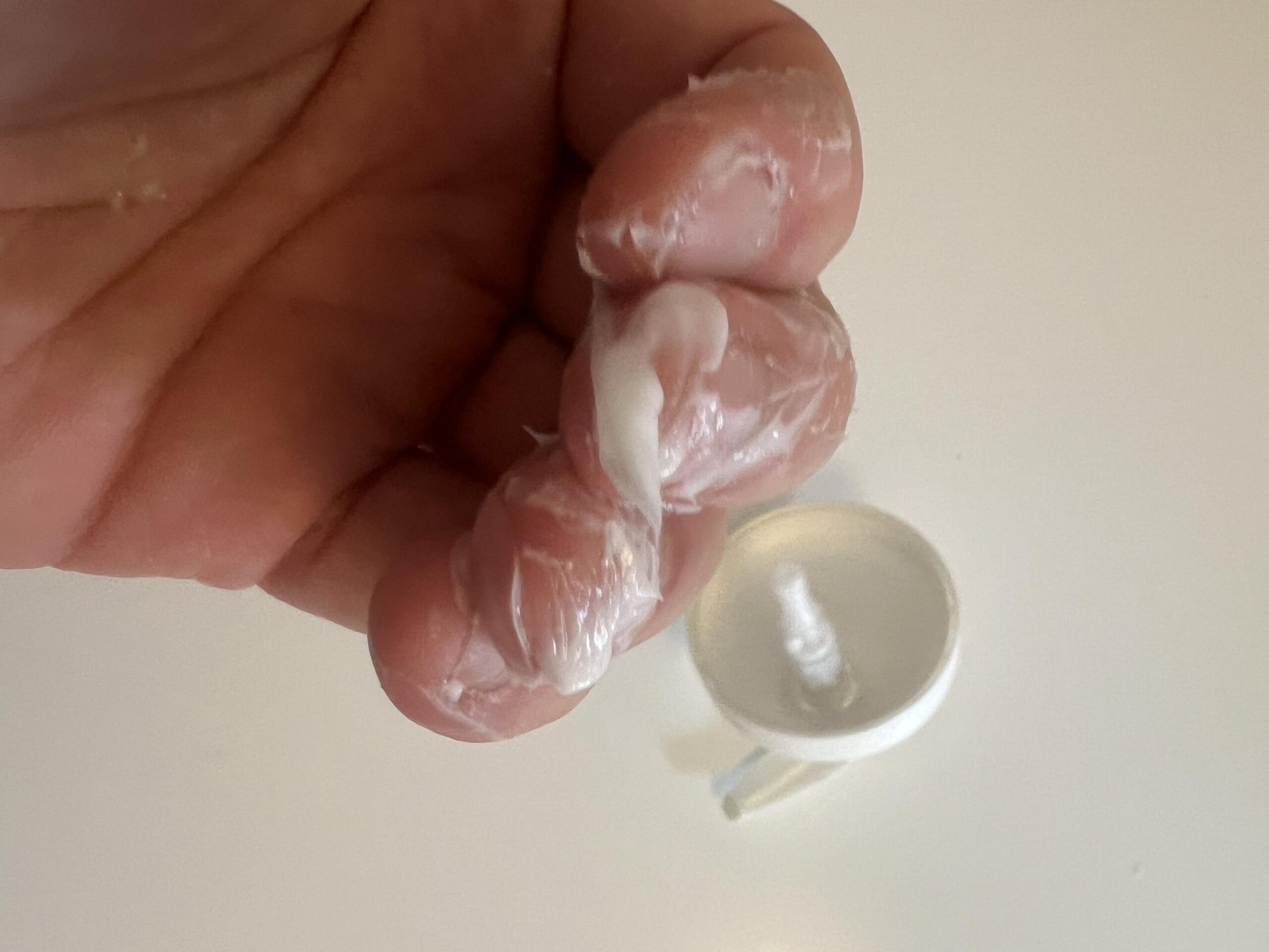 Close-up of white CeraVe Moisturising Cream texture between fingers