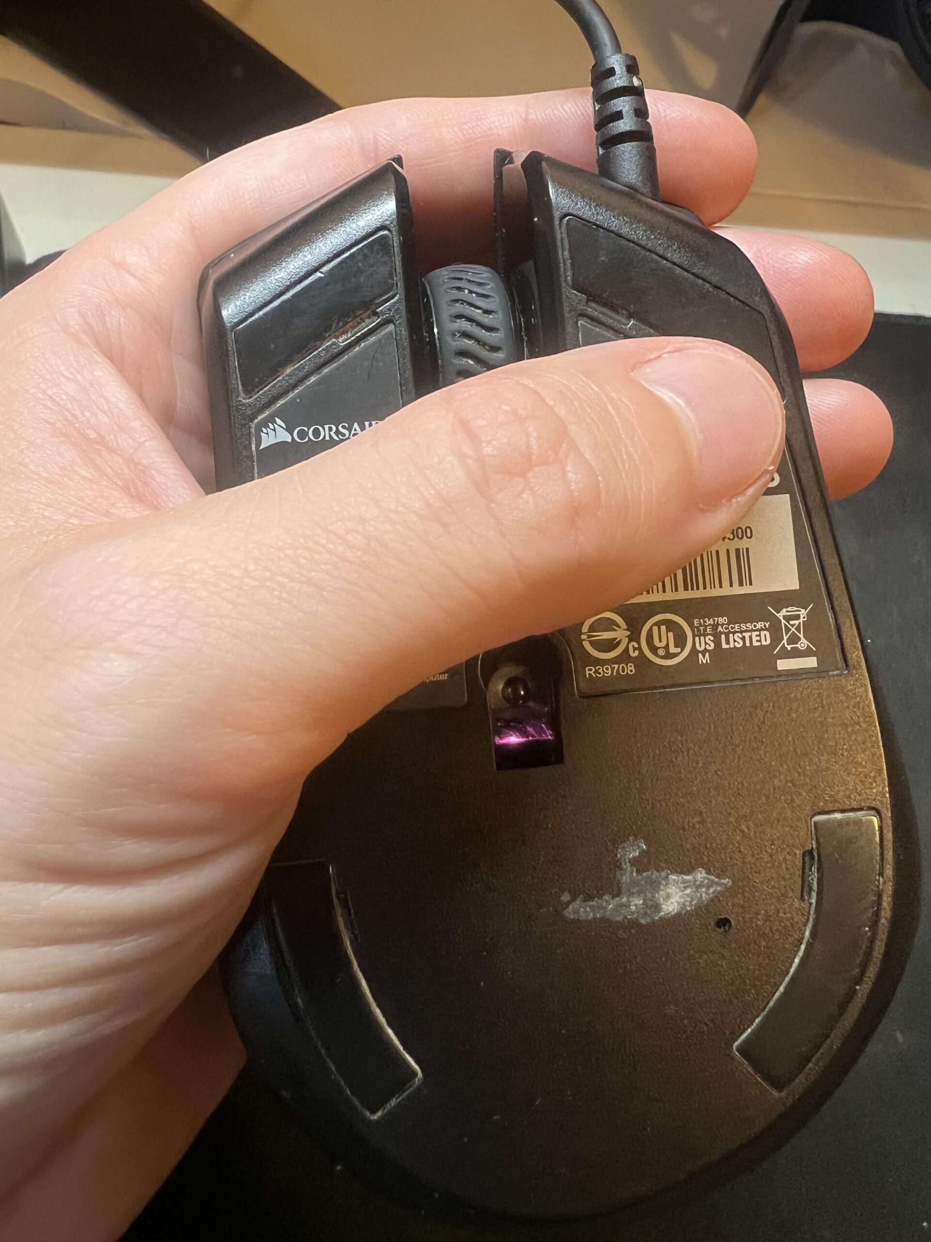 Unterseite der Corsair Harpoon RGB mit optischem Sensor, Mausfüßen und Produktetikett