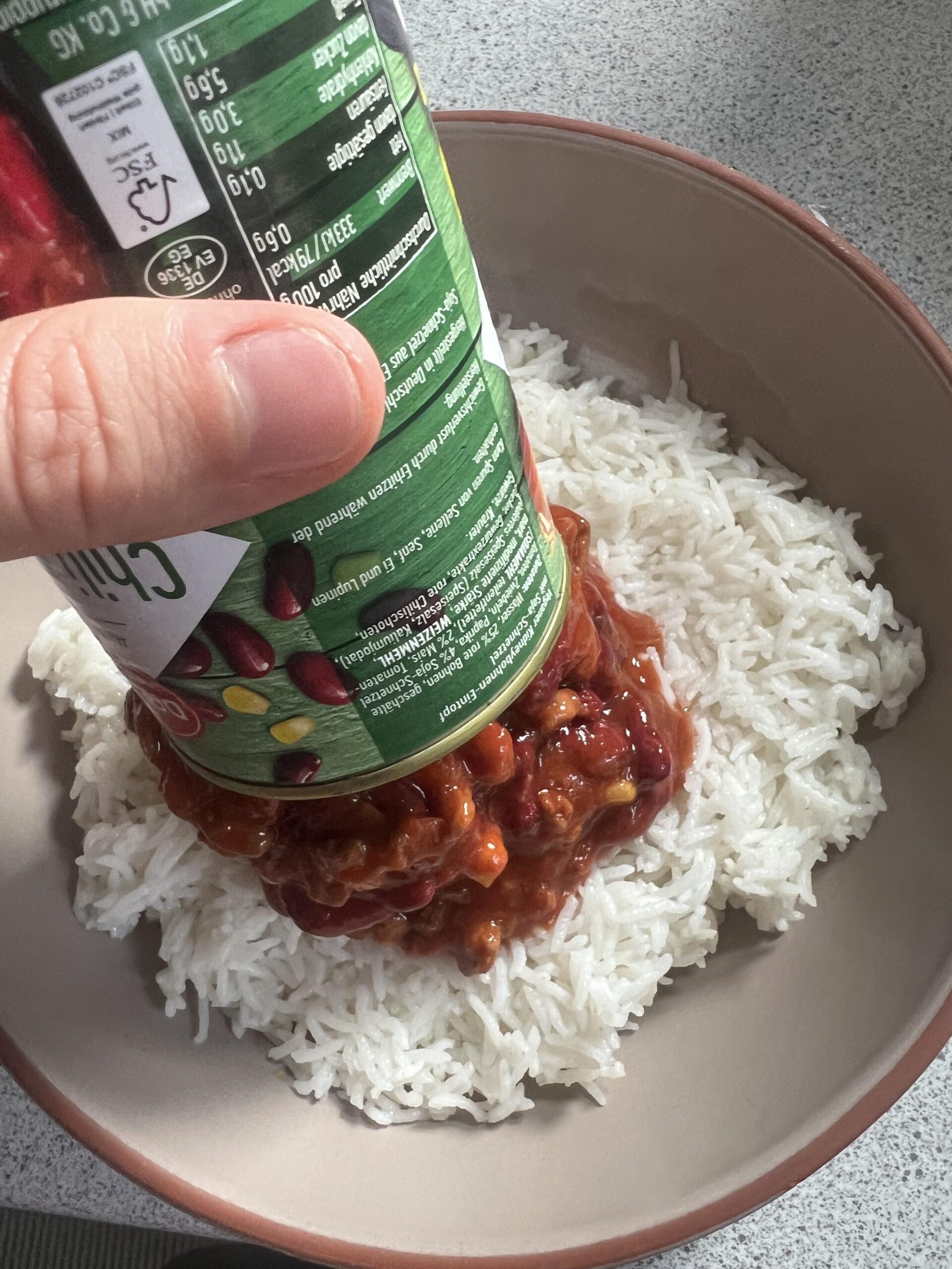 DREISTERN Chili sin Carne wird aus der Dose über gekochten Reis gegeben