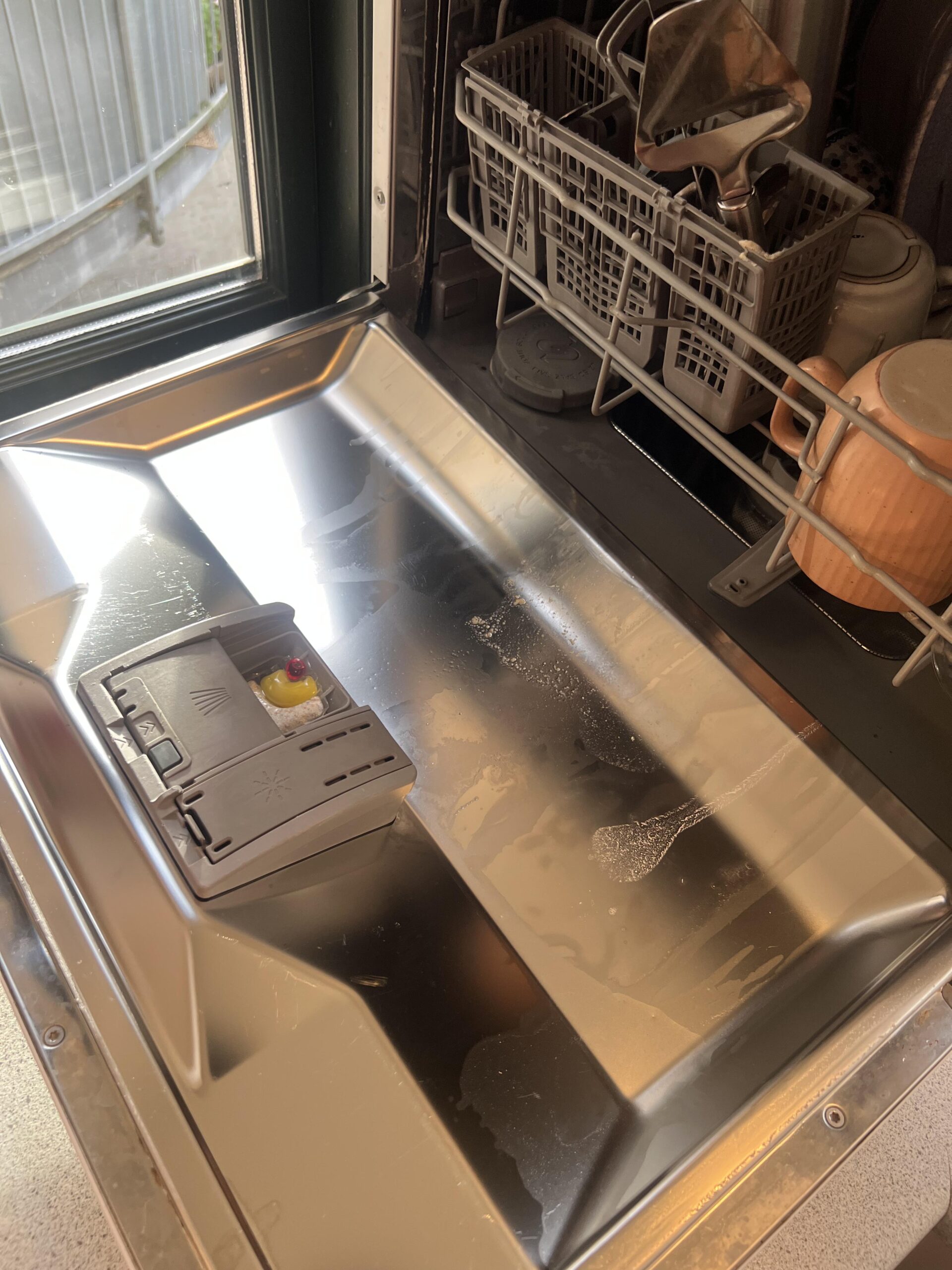 Original wider shot of open countertop dishwasher showing a Finish Ultimate Plus Citrus cap in the detergent tray