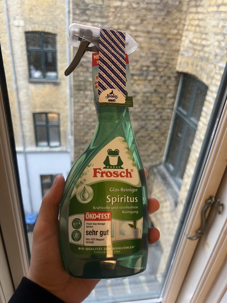 My Frosch Glas-Reiniger Spiritus 500 ml green spray bottle, front label visible, held by a window