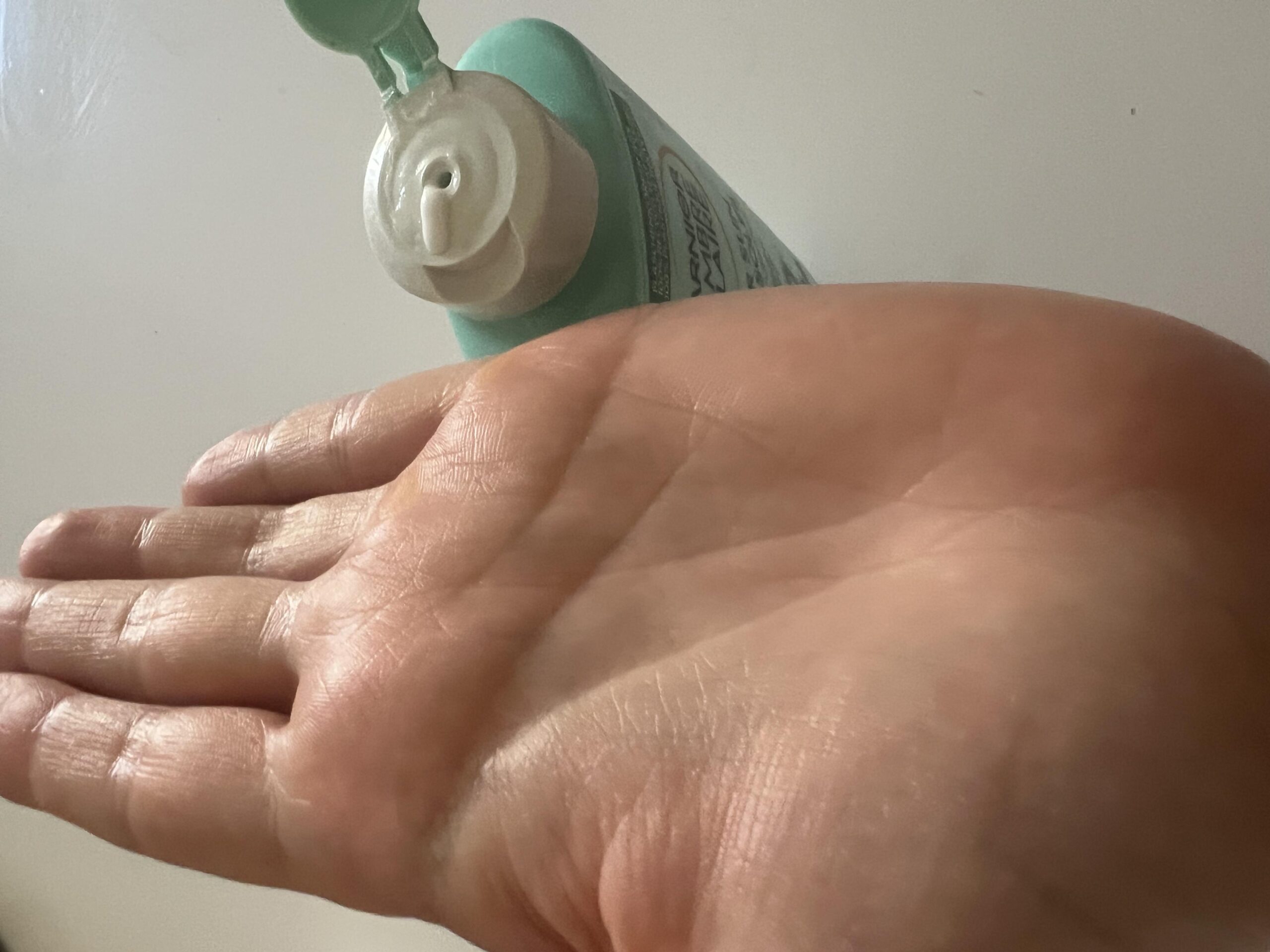 Original photo of an open hand near the Garnier After Sun lotion's dispensing nozzle