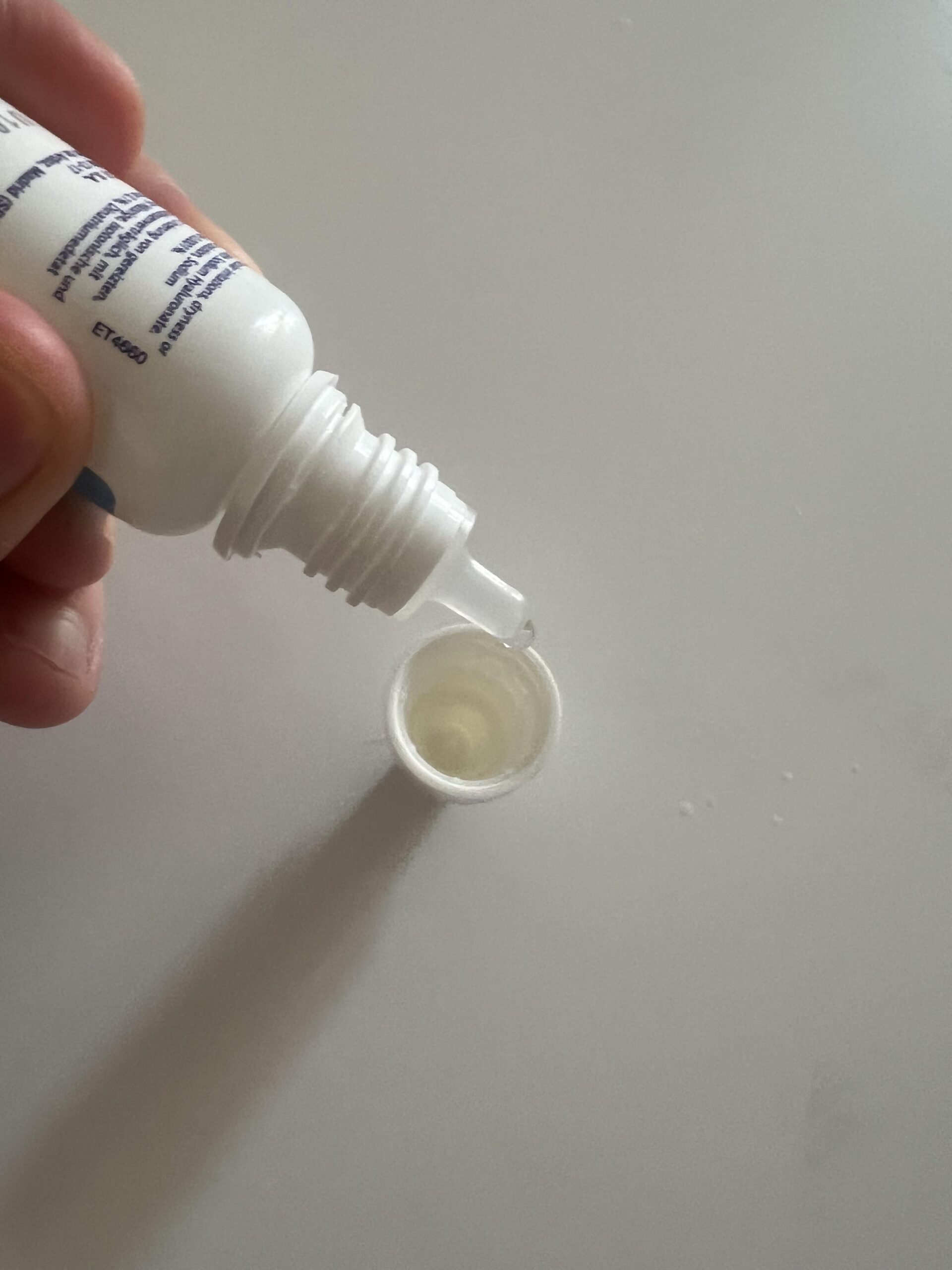 Glamlens eye-drop nozzle dispensing a small clear drop above the bottle cap in my original close-up photo