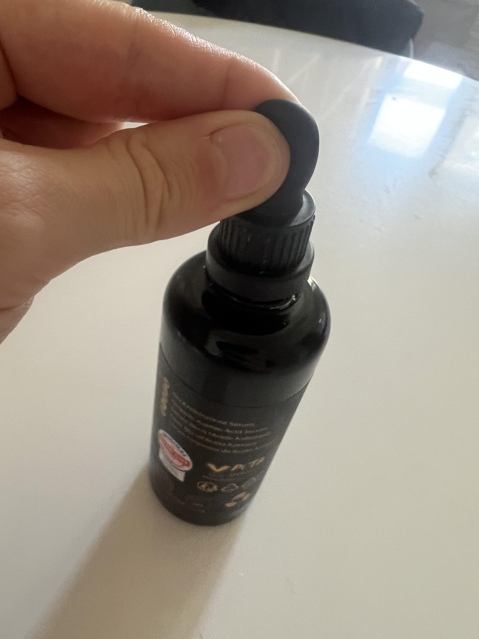 Original photo of the black dropper cap on the Kapua Naturals azelaic acid serum bottle held in my hand