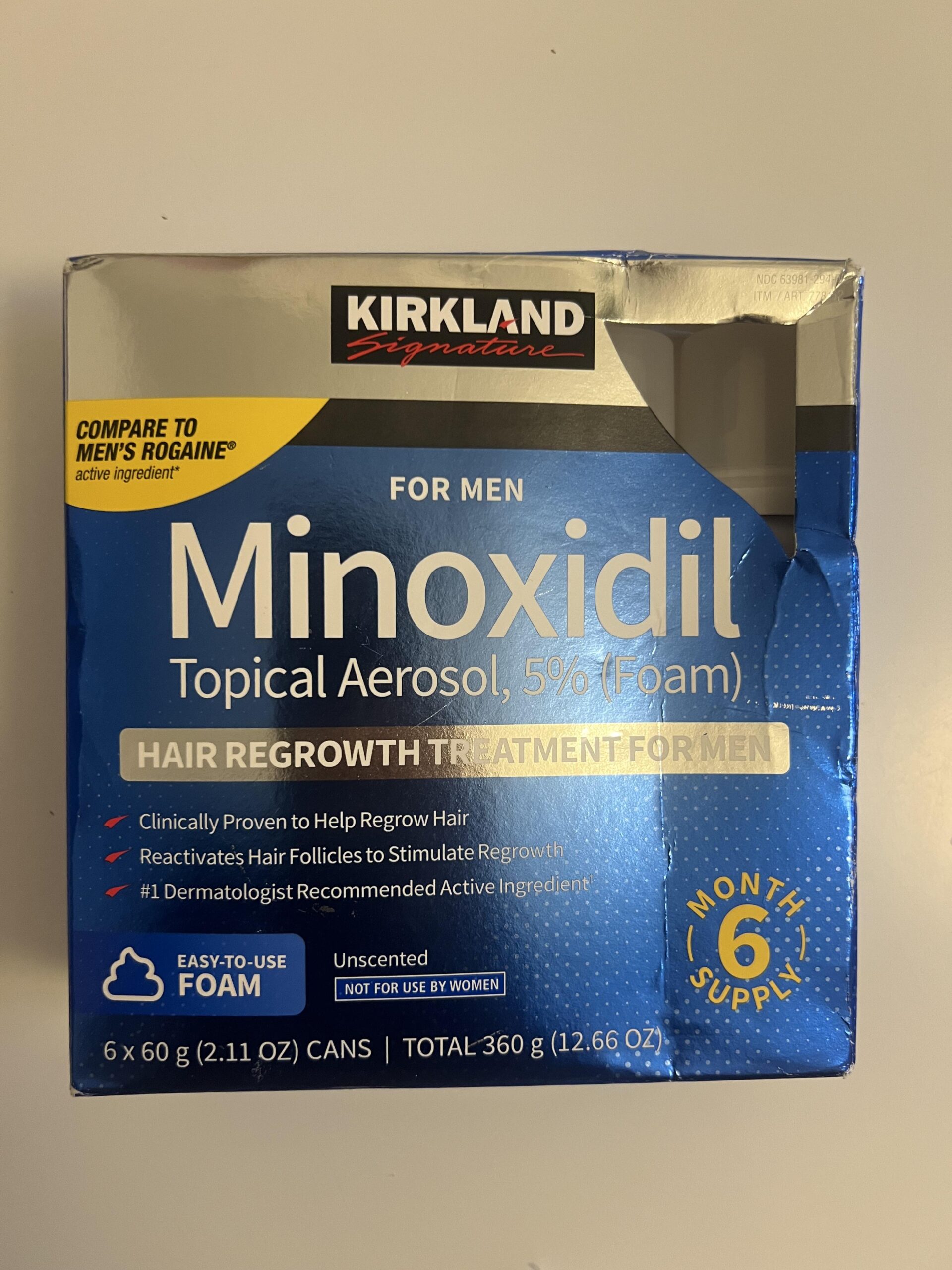 Original photo of a blue Kirkland Signature Minoxidil Topical Aerosol 5% Foam for Men box, 6 cans of 60 g, six-month supply