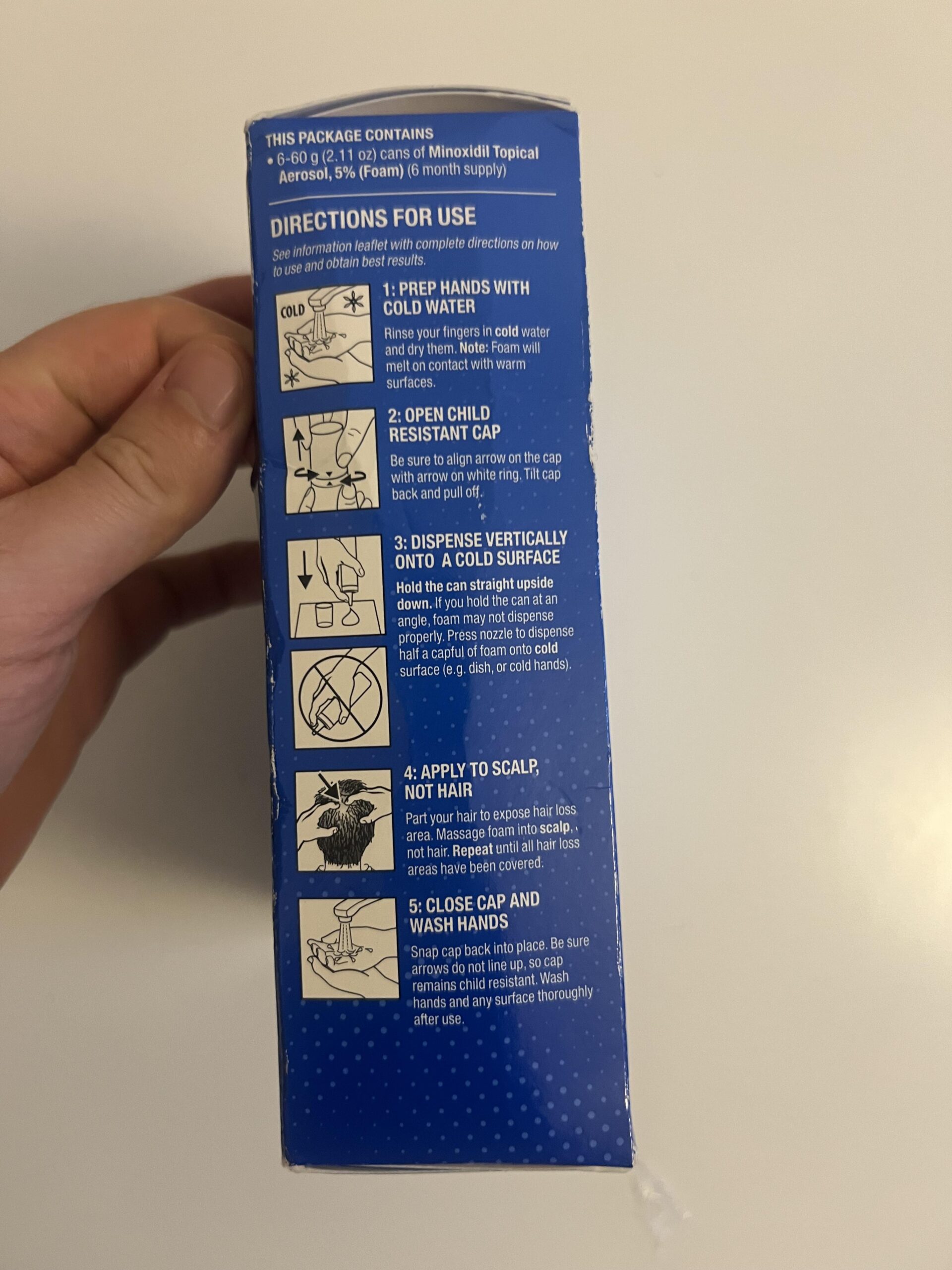 My Kirkland minoxidil foam carton side panel illustrating dispensing half a capful to a cold hand and applying foam to scalp