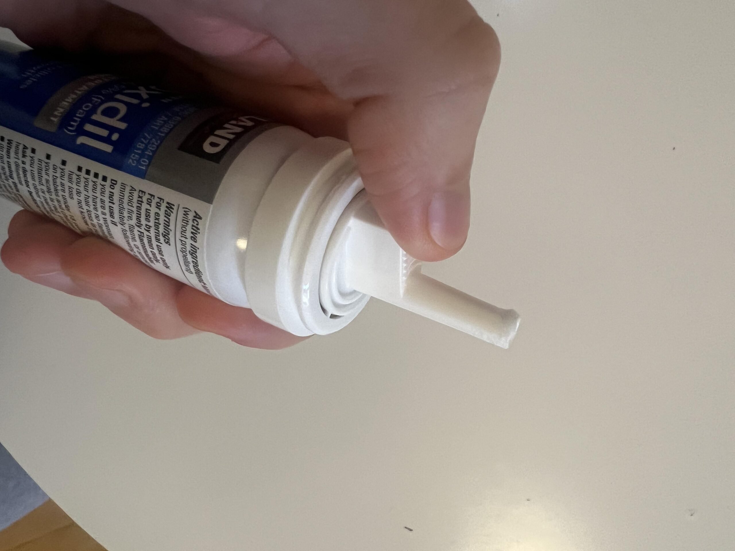 Close-up showing the white dispensing nozzle of my Kirkland minoxidil foam aerosol can