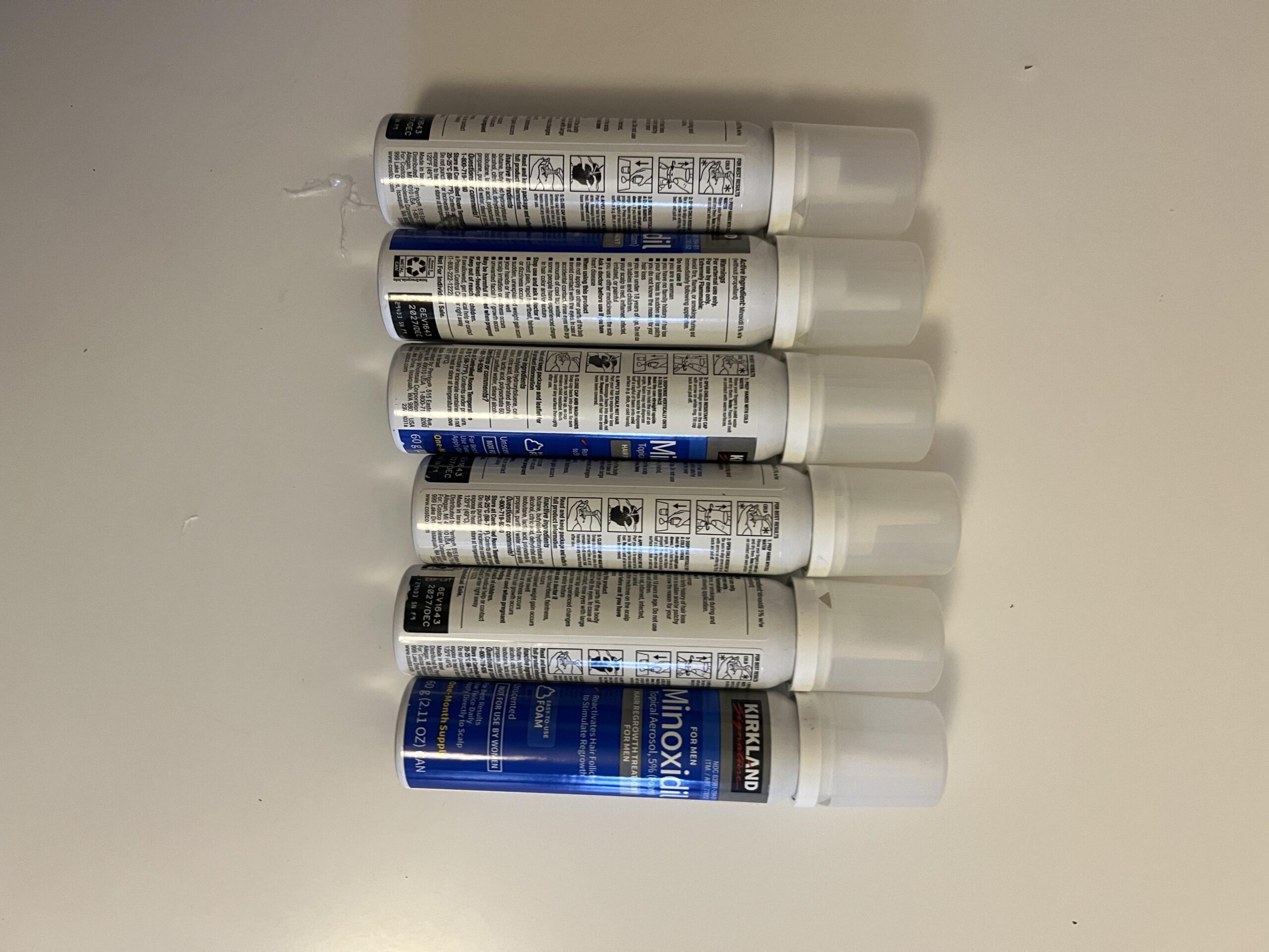 Original photograph of all six sixty gram Kirkland minoxidil five percent foam aerosol cans together
