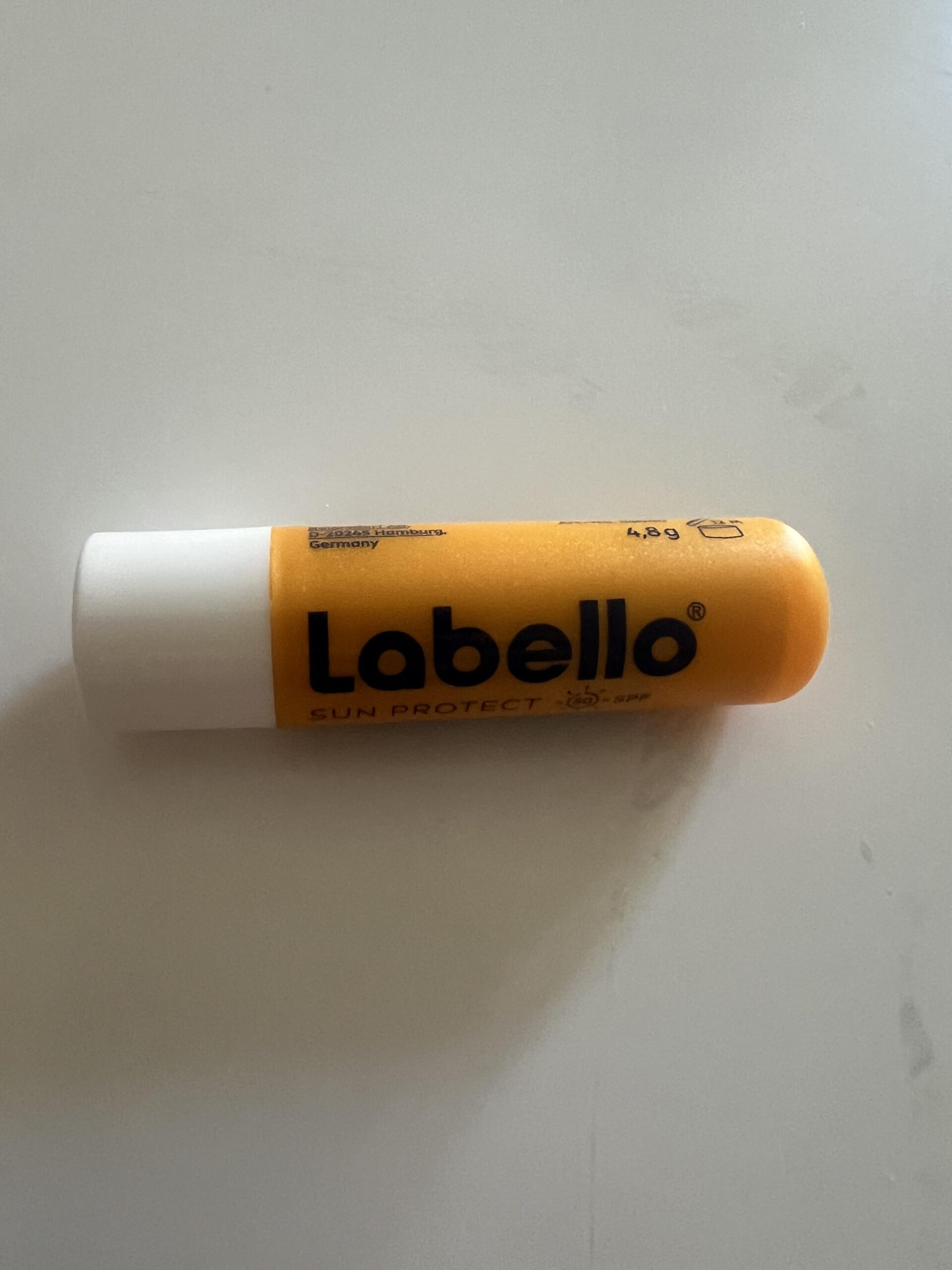 Labello Sun Protect SPF 50 orange lip balm tube lying flat, photographed from the front