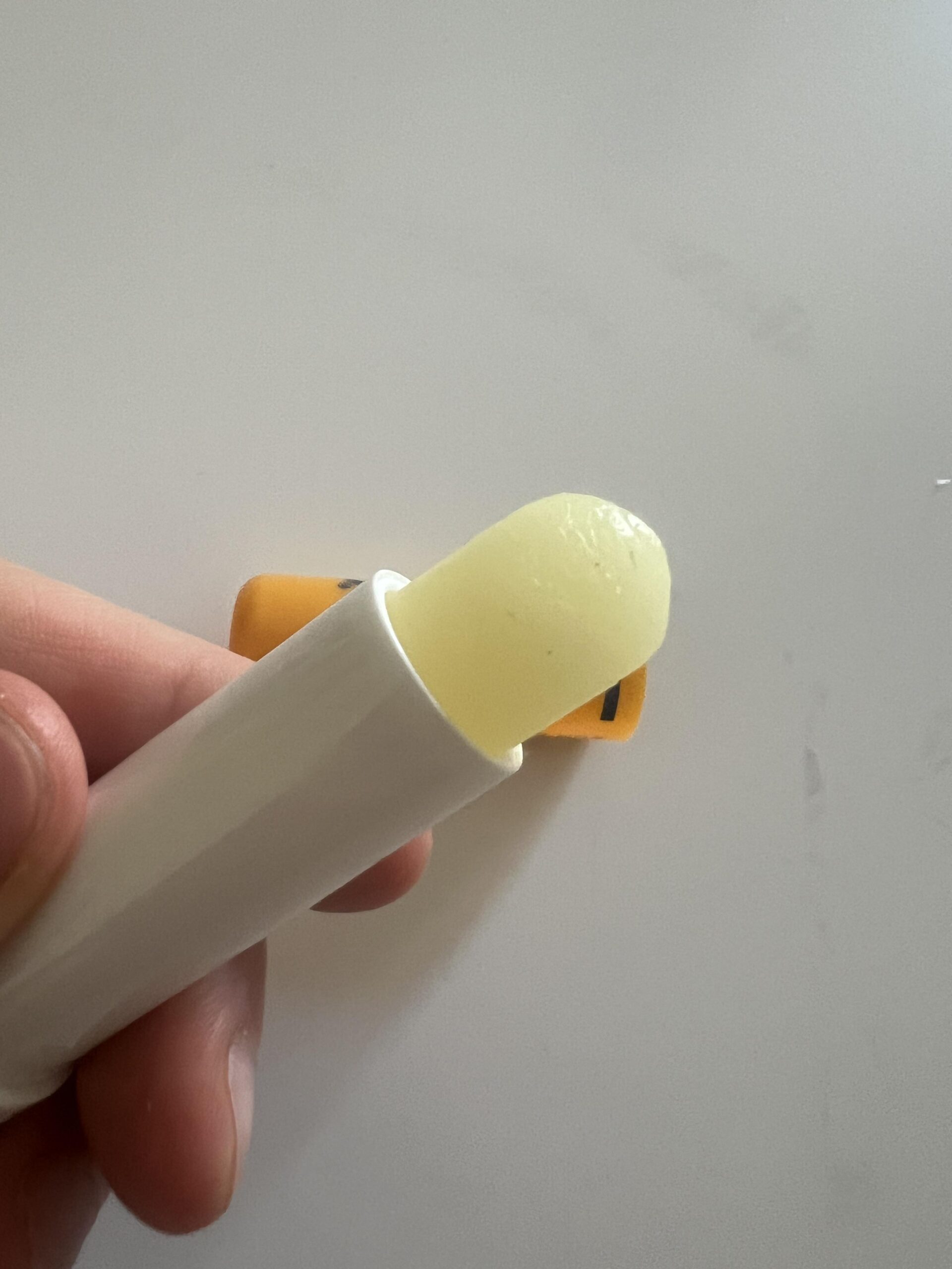 Close-up of the pale yellow Labello Sun Protect balm protruding from its white stick holder