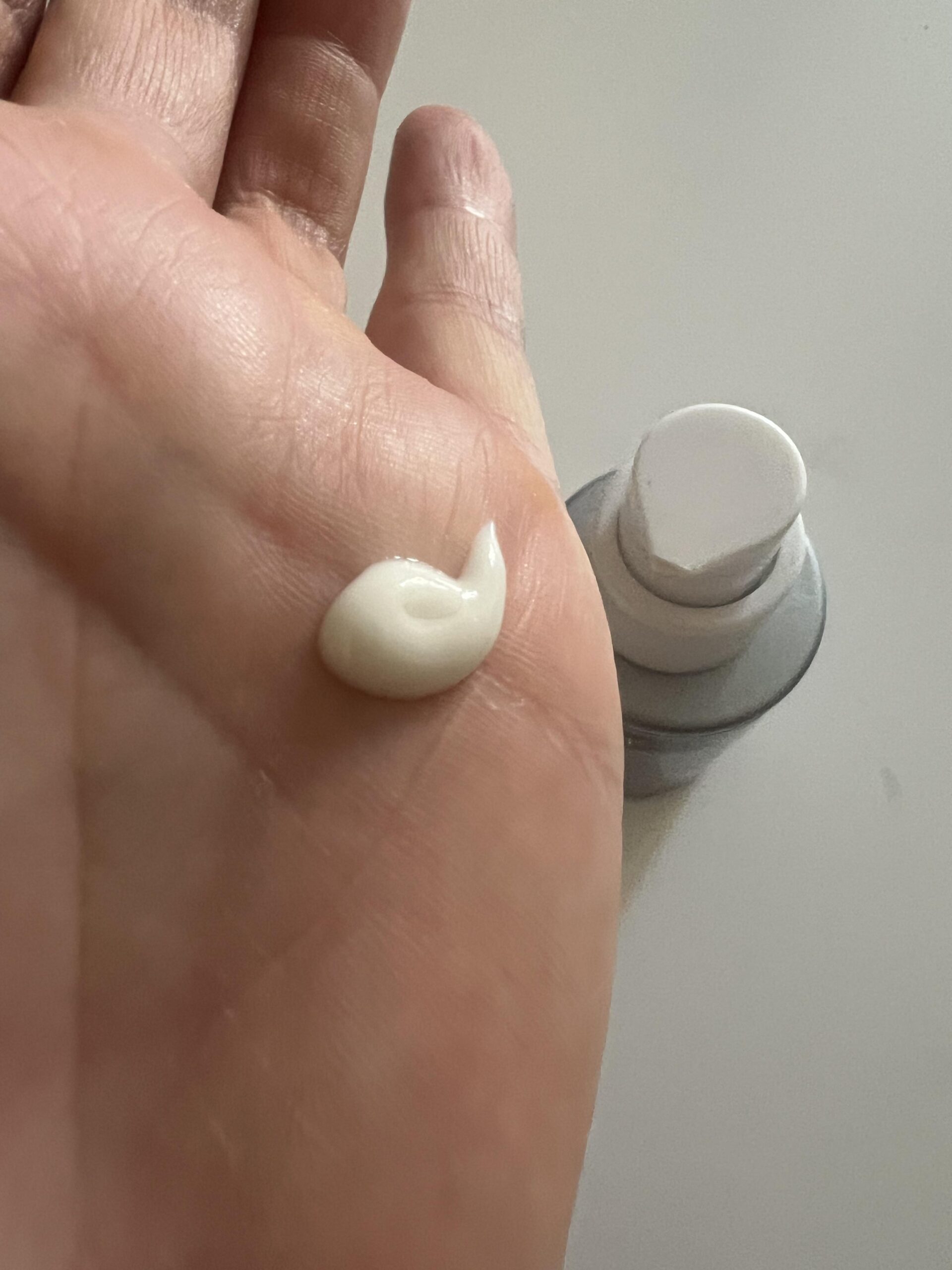 My genuine photo showing the white Neutrogena Retinol Boost night cream on my palm next to the pump bottle
