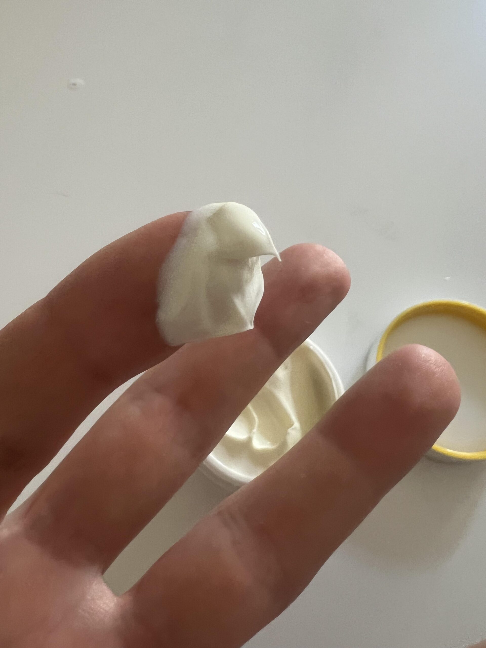 White NIVEA Q10 day cream held on fingertip over the open SPF 30 jar