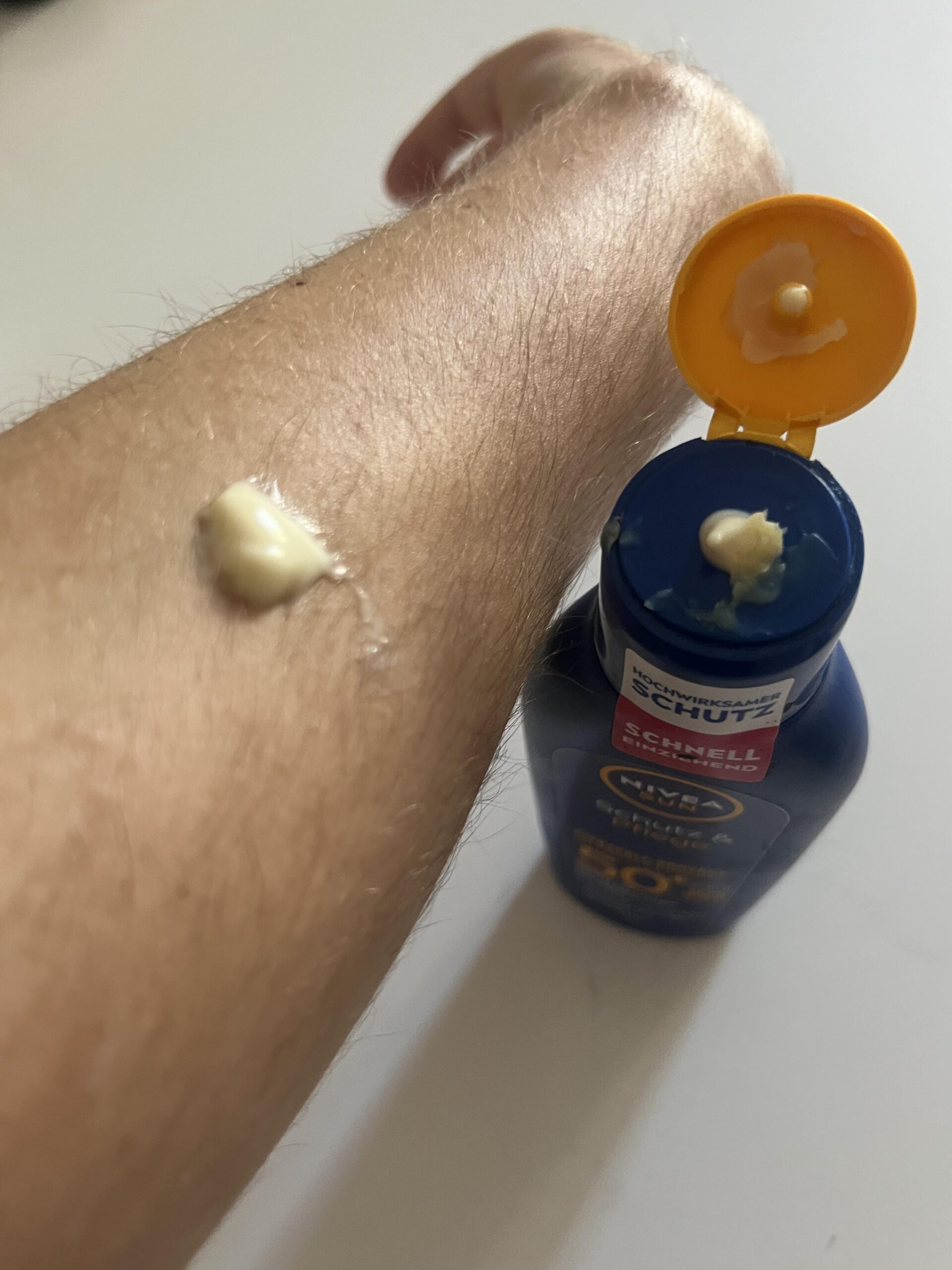 Original first-hand photograph of a dollop of NIVEA SUN SPF 50 plus lotion on my forearm next to the opened bottle
