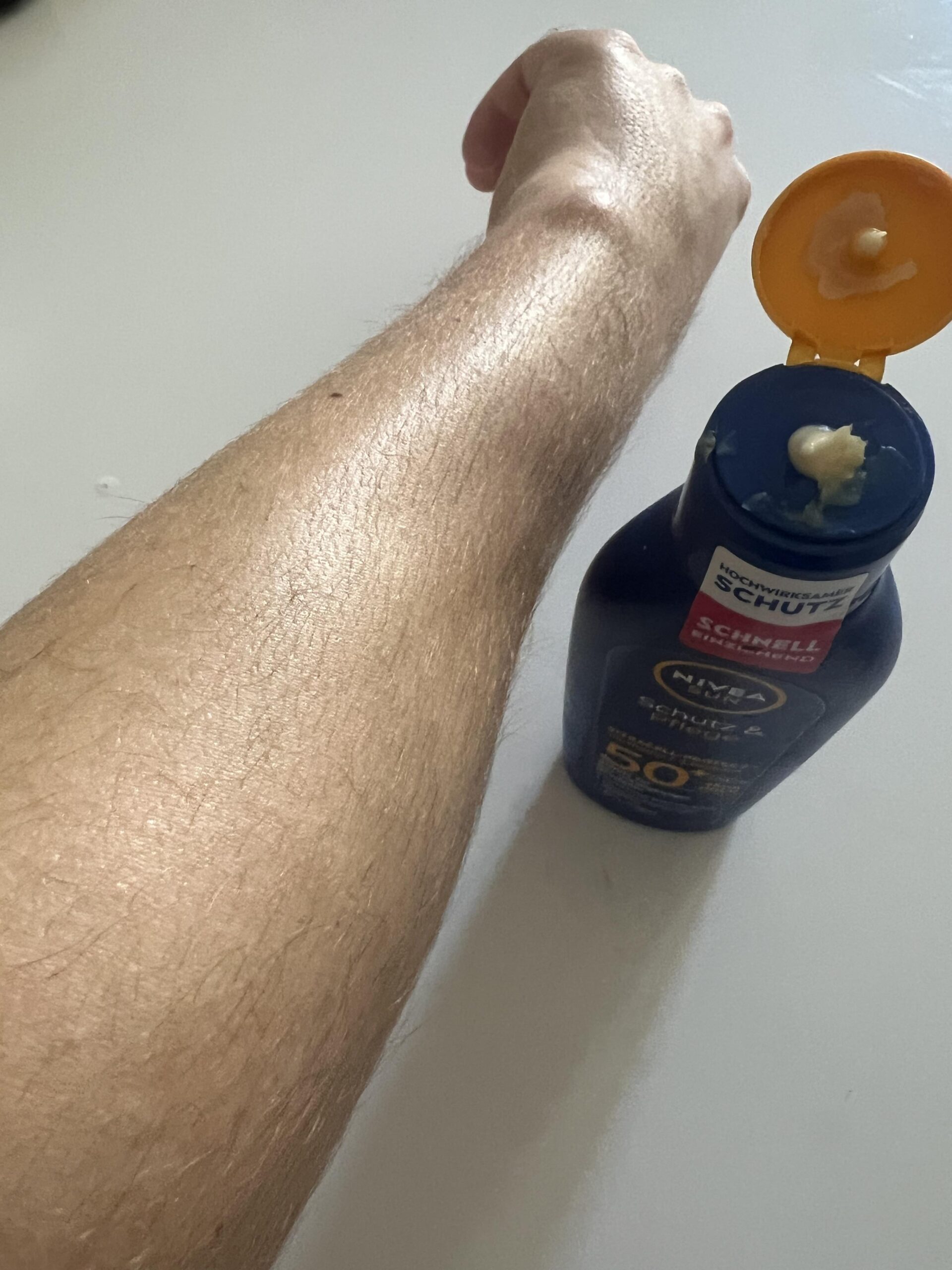Original photograph of my forearm after rubbing in NIVEA SUN SPF 50 plus body lotion next to the opened bottle