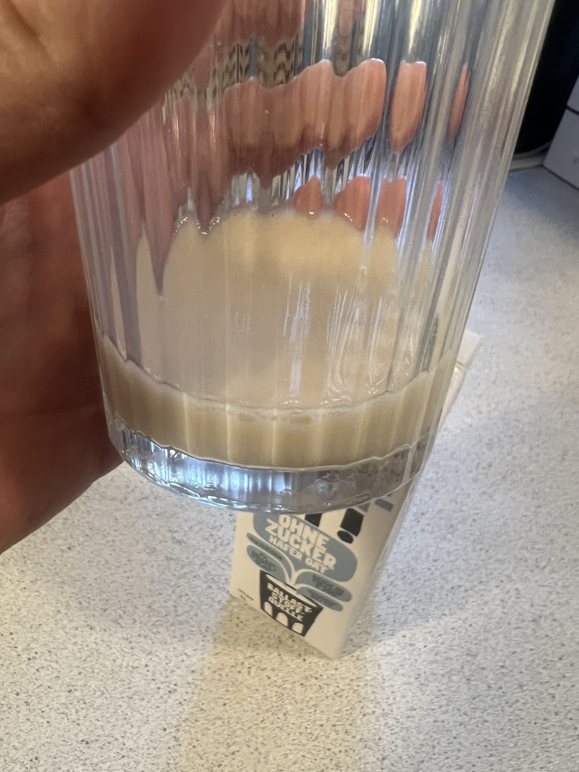 Original photograph of beige Oatly No Sugars oat drink poured into a clear ridged glass