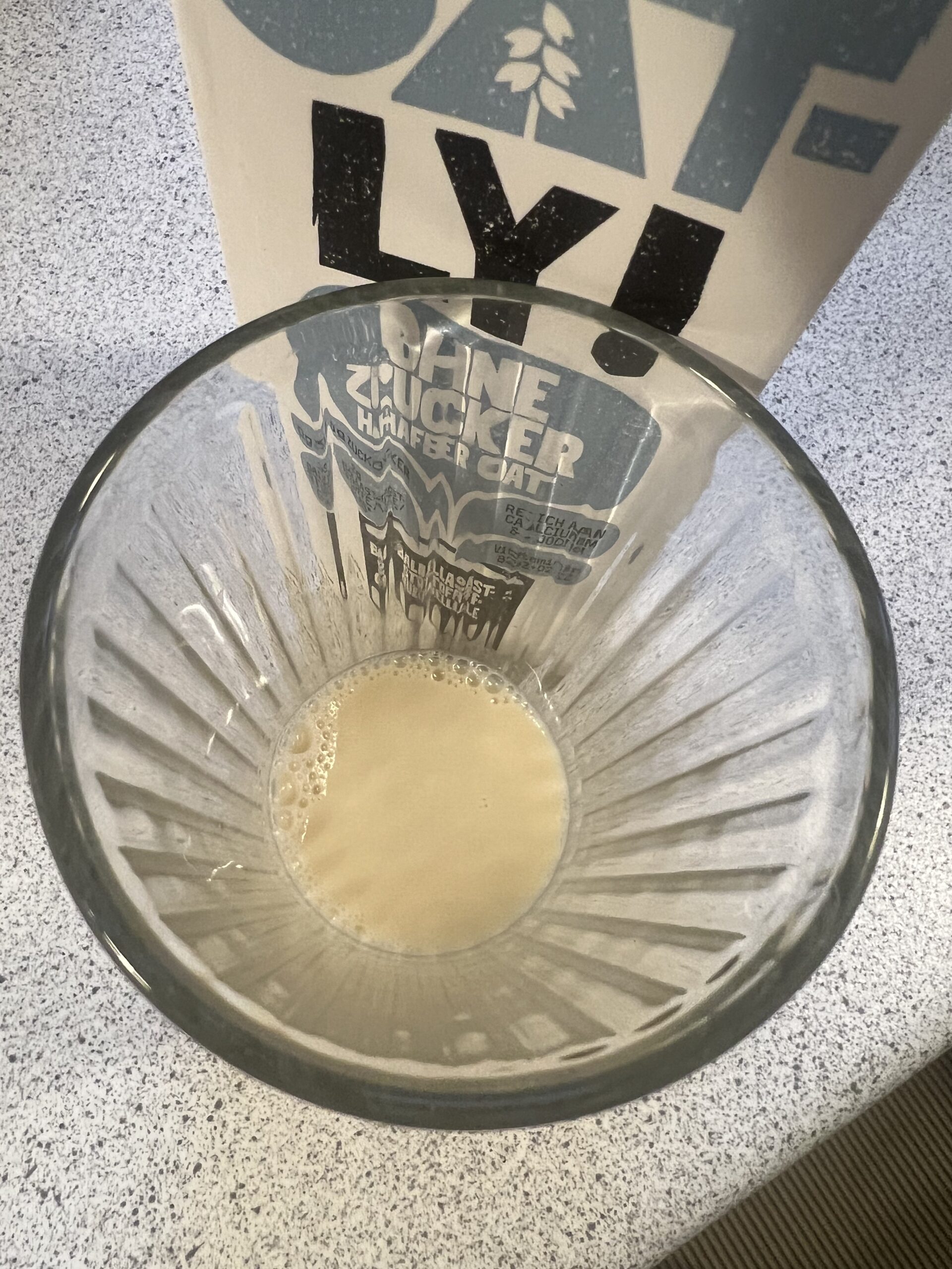 Original overhead photo of Oatly No Sugars oat drink in a drinking glass