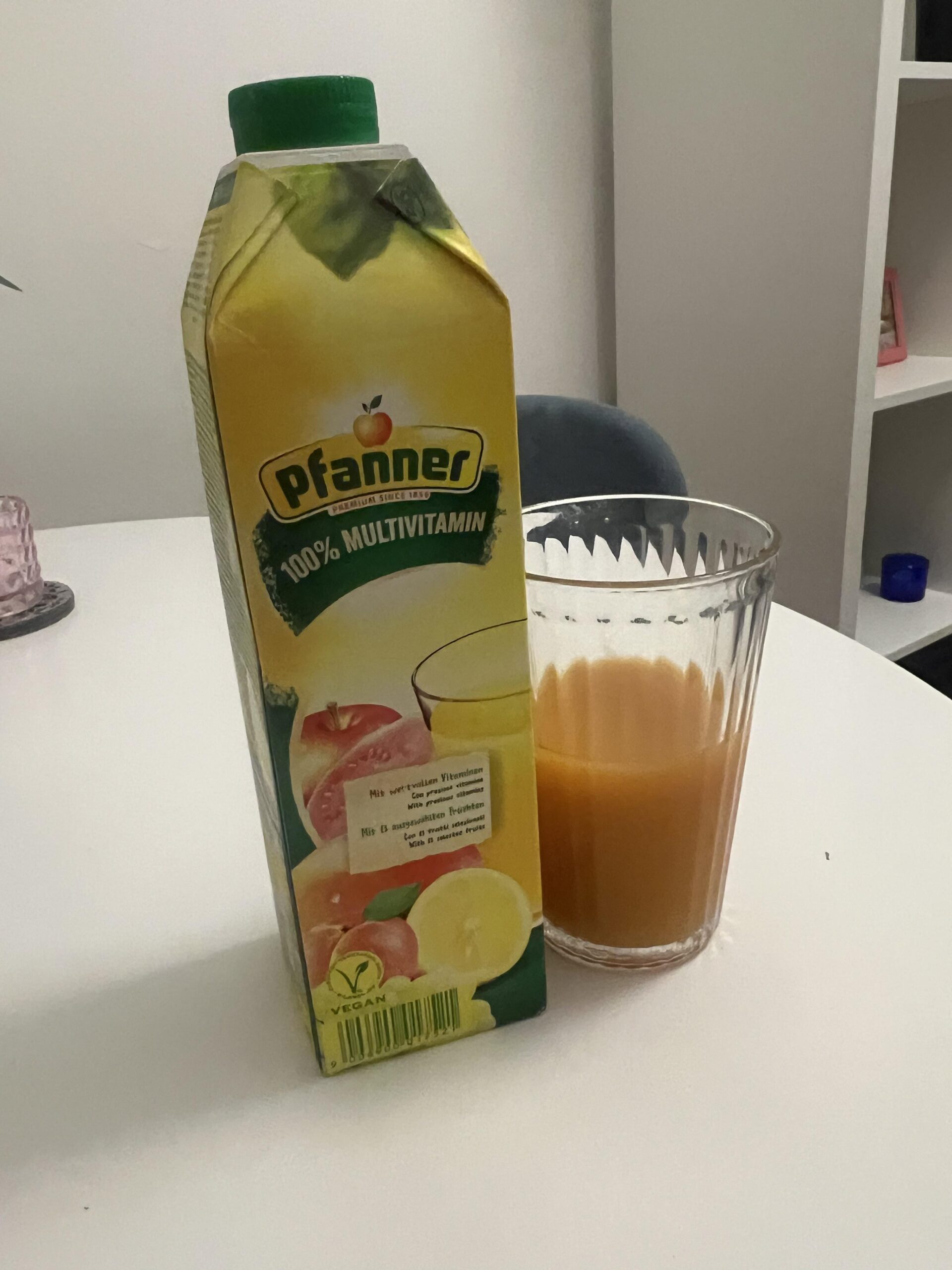 Pack de Pfanner 100% Multi-Vitamin de 8 x 1 litro con un cartón y un vaso de zumo