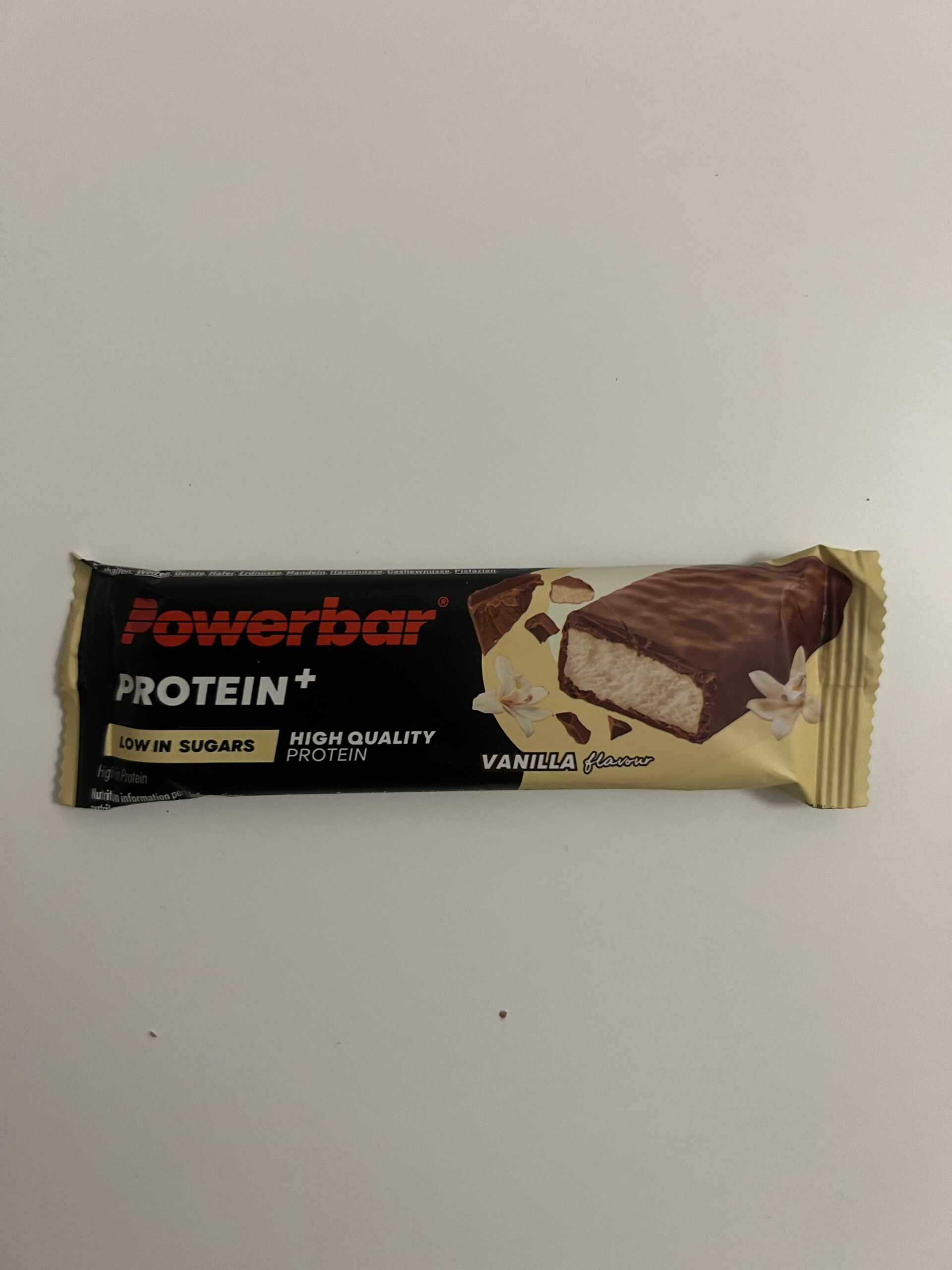 Original photo of a PowerBar Protein+ Low in Sugars Vanilla 35g chocolate-coated bar in its black and gold wrapper