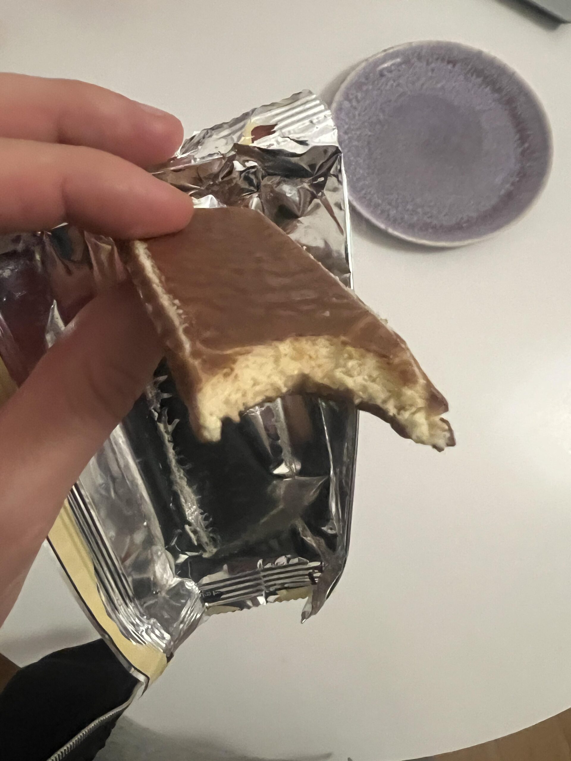 A bitten PowerBar Protein+ Vanilla bar showing chocolate coating and soft, pale filling