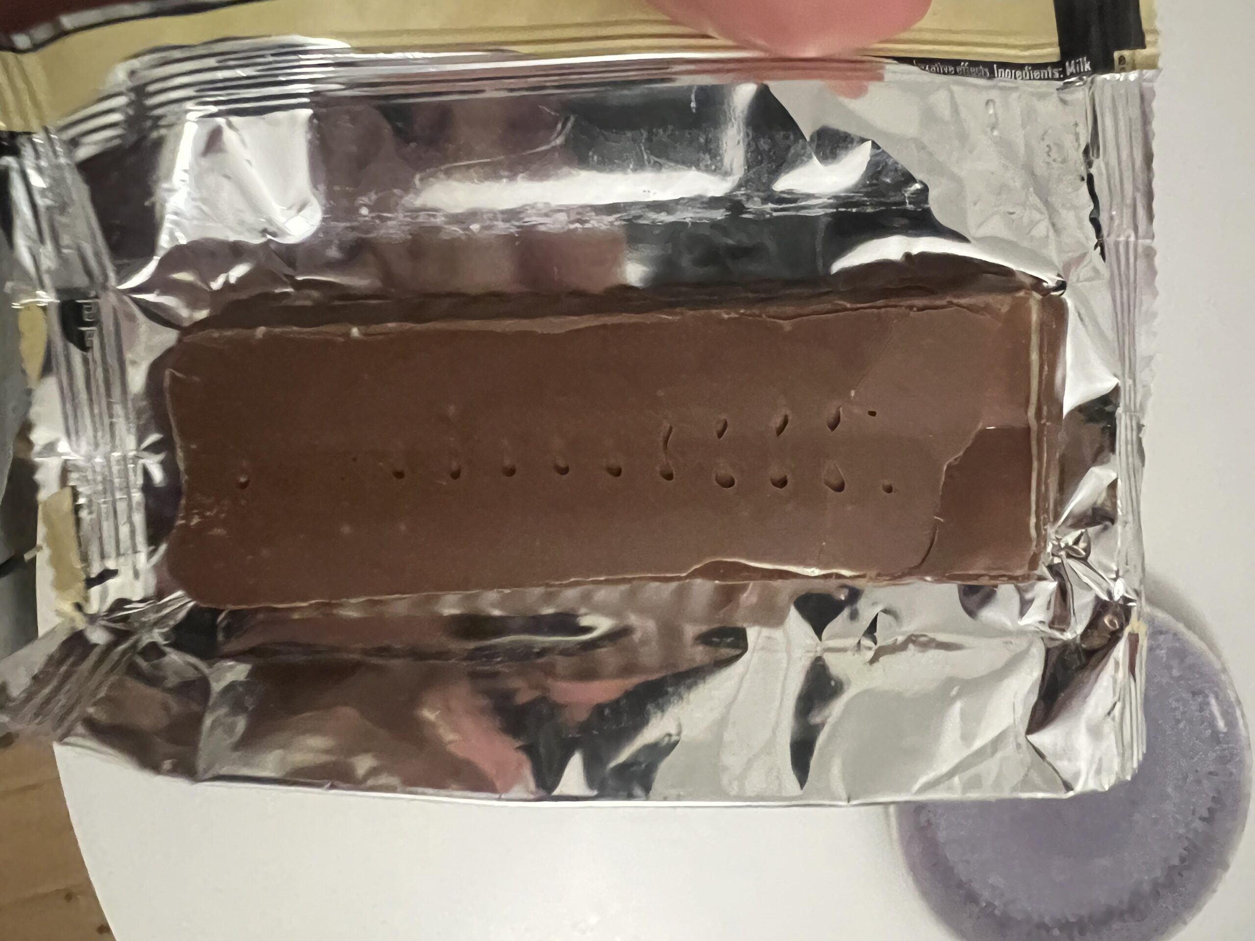 Smooth underside of an unwrapped PowerBar Vanilla protein bar resting in its foil