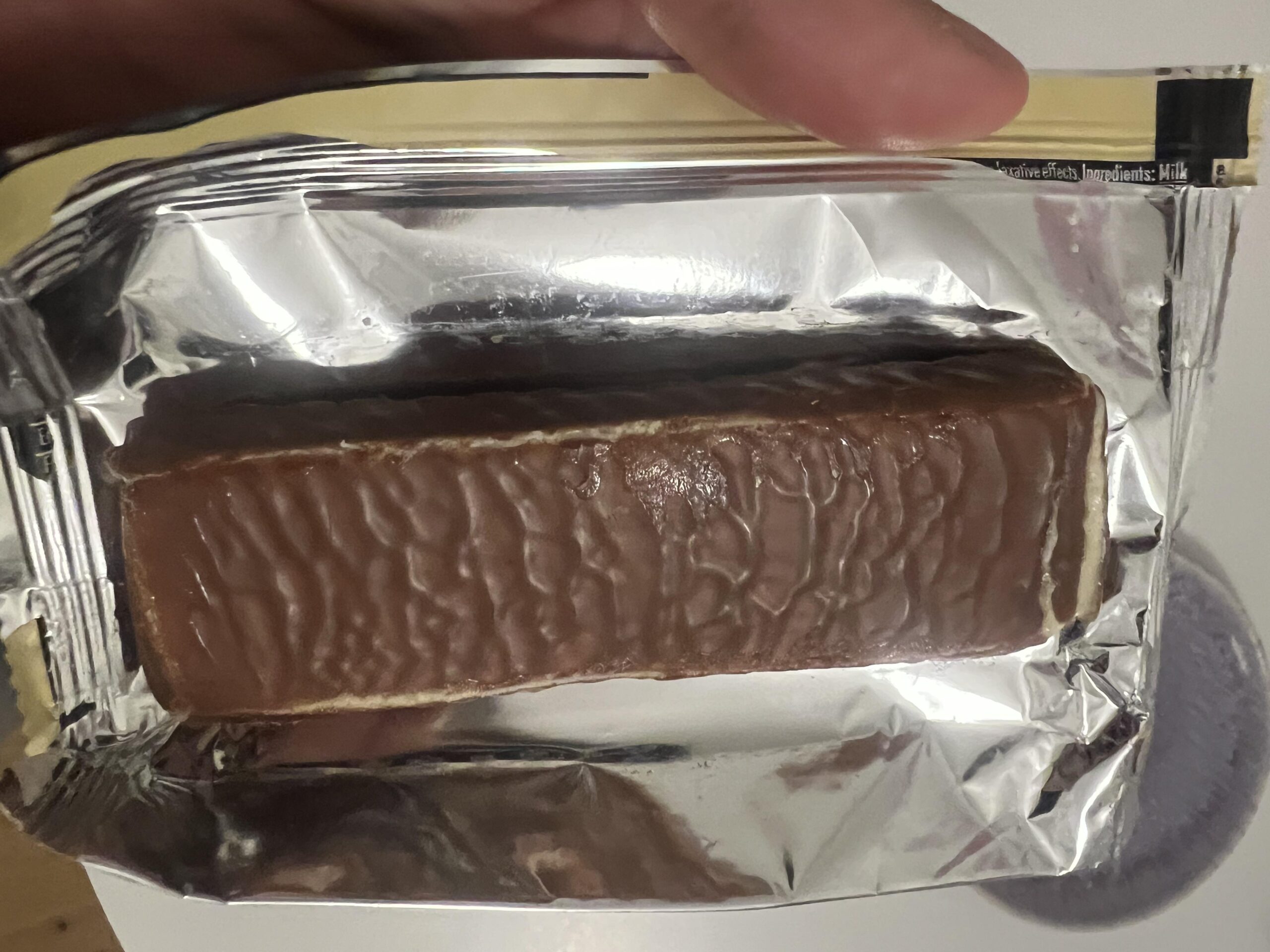 Unwrapped PowerBar Protein+ Vanilla bar showing the rippled chocolate coating
