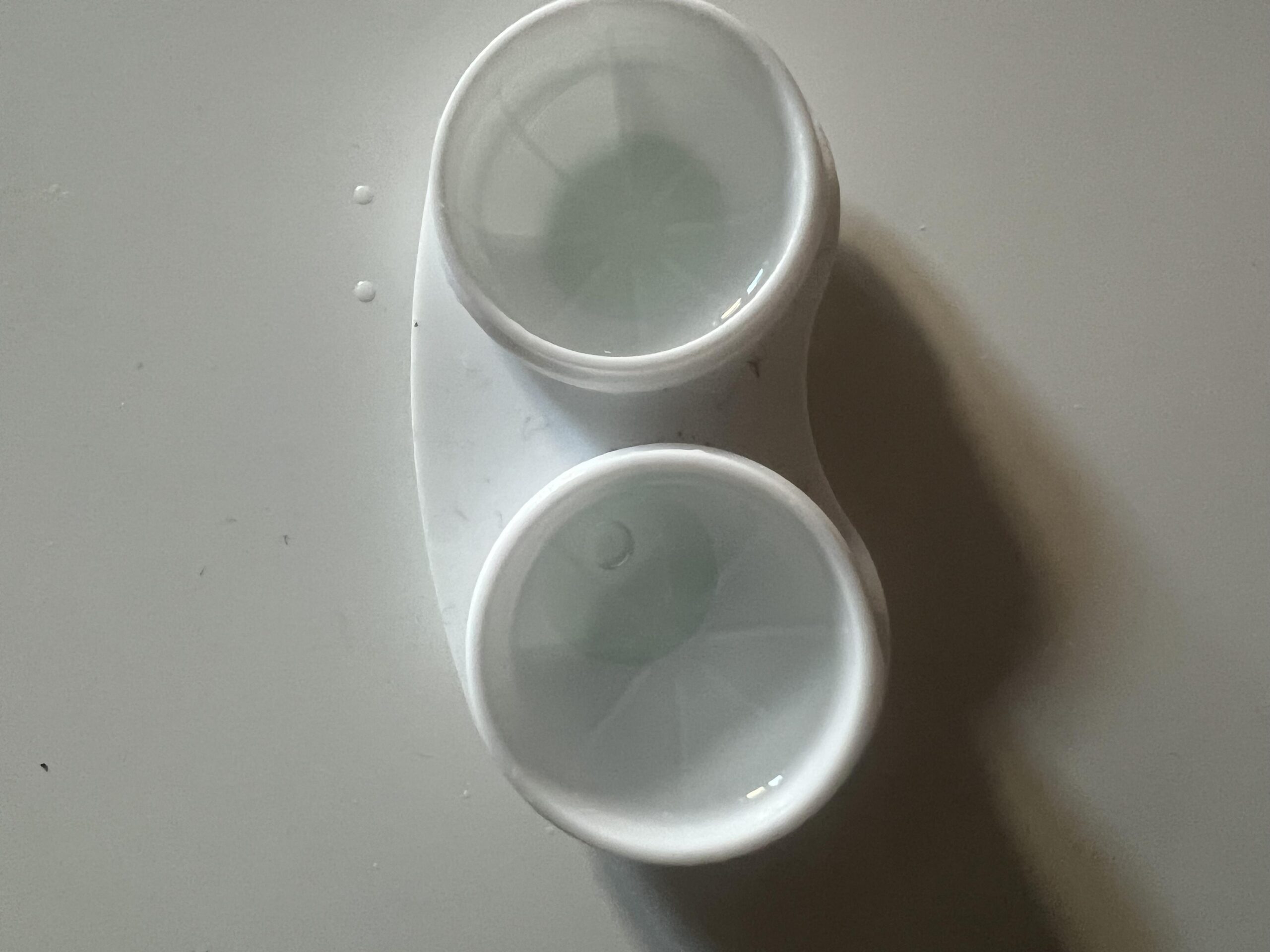 Open white two-well contact lens case photographed from above
