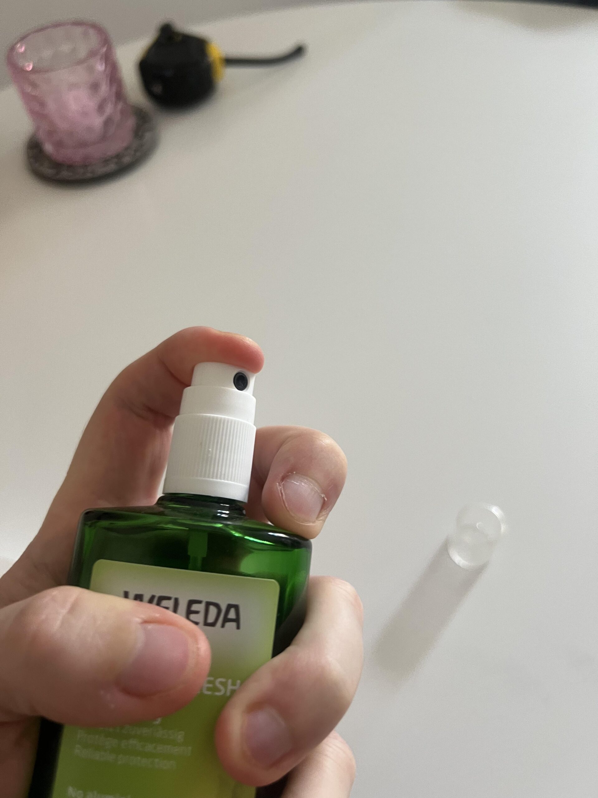 My hand holding a Weleda Citrus Fresh Deo Spray 100 ml bottle with finger resting on the pump